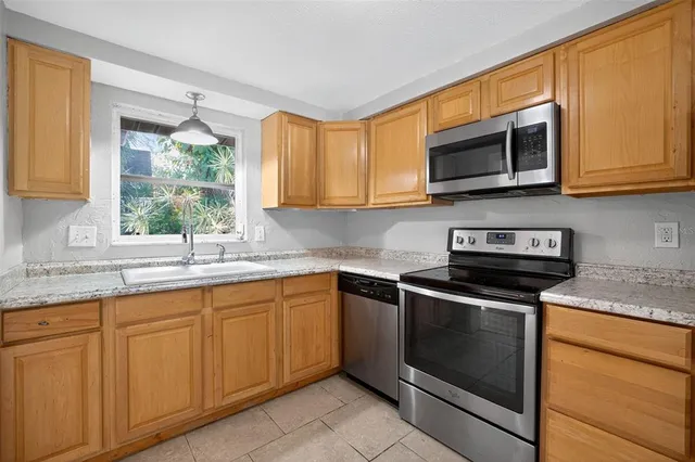 a kitchen with stainless steel appliances granite countertop white cabinets granite counter tops and a window