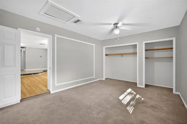 an empty room with closet and a chandelier fan
