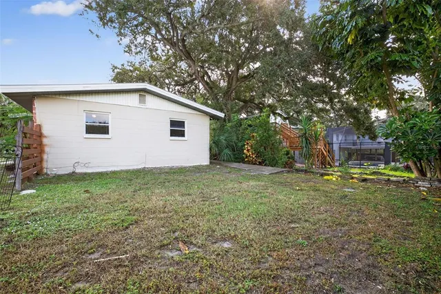 a view of a backyard with plants and large tree