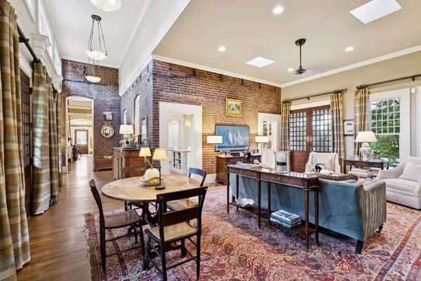 a view of a patio with couches table and chairs with potted plants and a large window