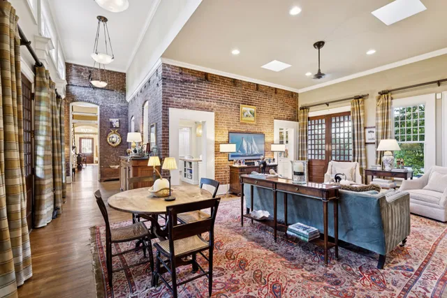a view of a patio with couches table and chairs with potted plants and a large window