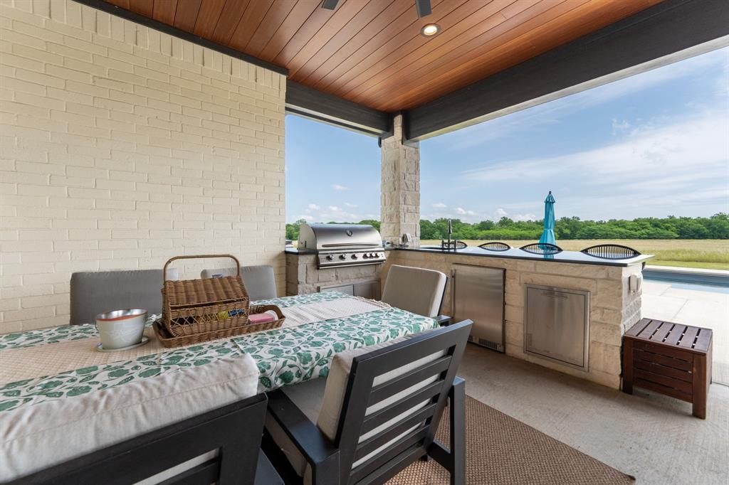 2396 County Road 2145 Cooper, TX 75432 - Photo 25 of 37 Covered outdoor patio featuring a wood-finish ceiling, built-in outdoor kitchen with stainless steel appliances, stone base, and a black countertop