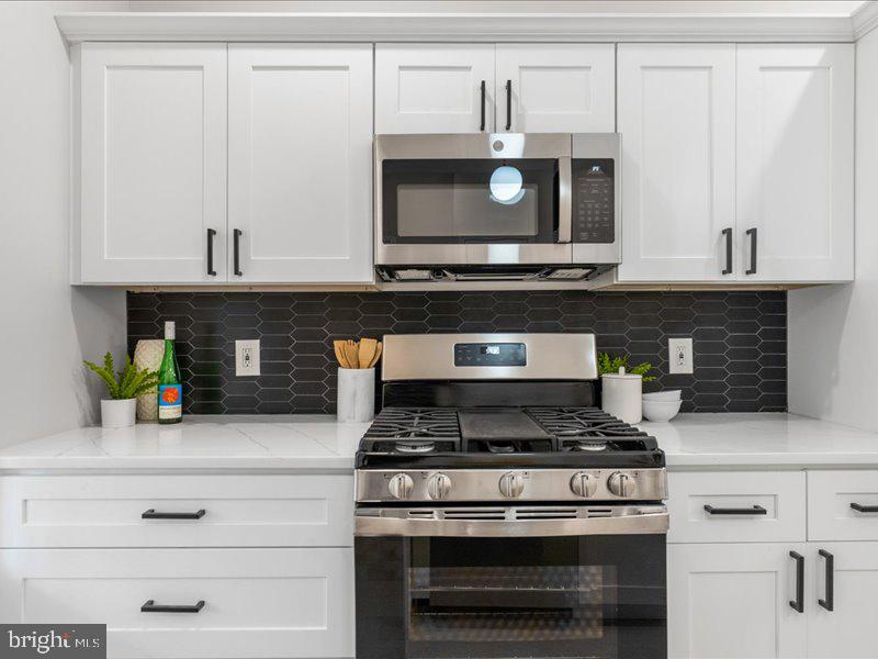 1645 Normal Avenue Baltimore, MD 21213 - Photo 15 of 53 a stove top oven sitting inside of a kitchen and white cabinets