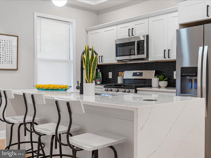 1645 Normal Avenue Baltimore, MD 21213 - Photo 27 of 53 a kitchen with stainless steel appliances kitchen island granite countertop a refrigerator and a stove top oven