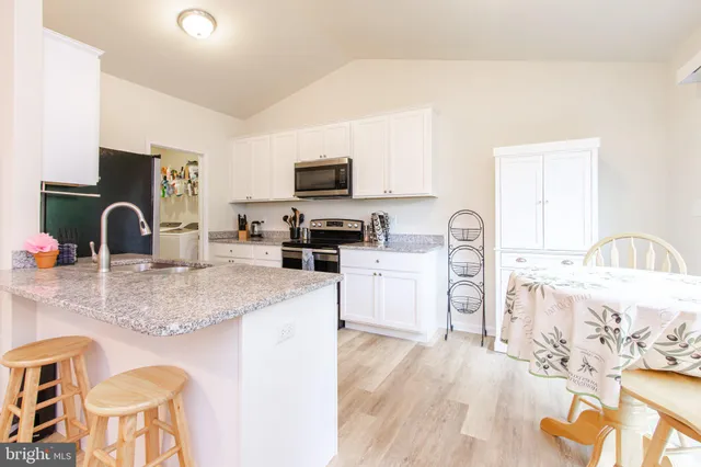 a kitchen with stainless steel appliances granite countertop a sink a stove top oven a dining table and chairs with wooden floor