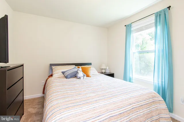 a bedroom with a bed and a flat tv screen next to a window
