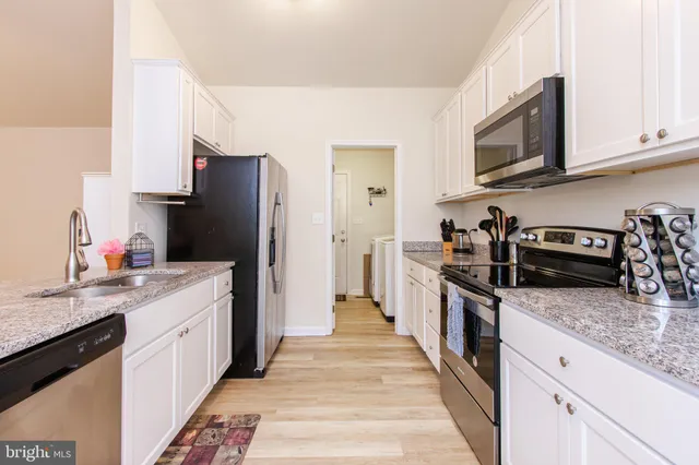 a kitchen with stainless steel appliances granite countertop a refrigerator a stove top oven a sink and dishwasher