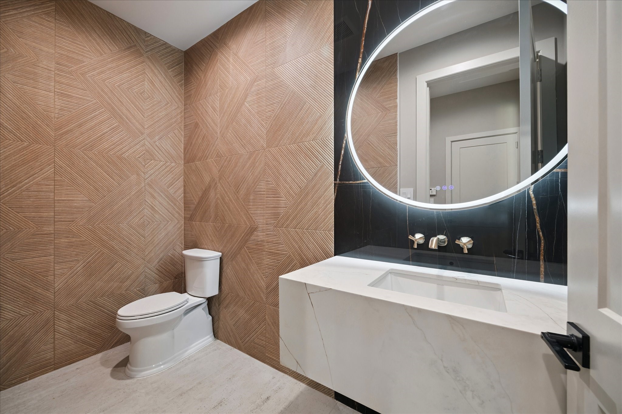 2120 Branard Street Houston, TX 77098 - Photo 13 of 33 This elegant half bathroom features textured tile walls that create a sophisticated backdrop. A floating sink is paired with a modern lighted mirror, combining sleek design with functionality for a striking contemporary look.