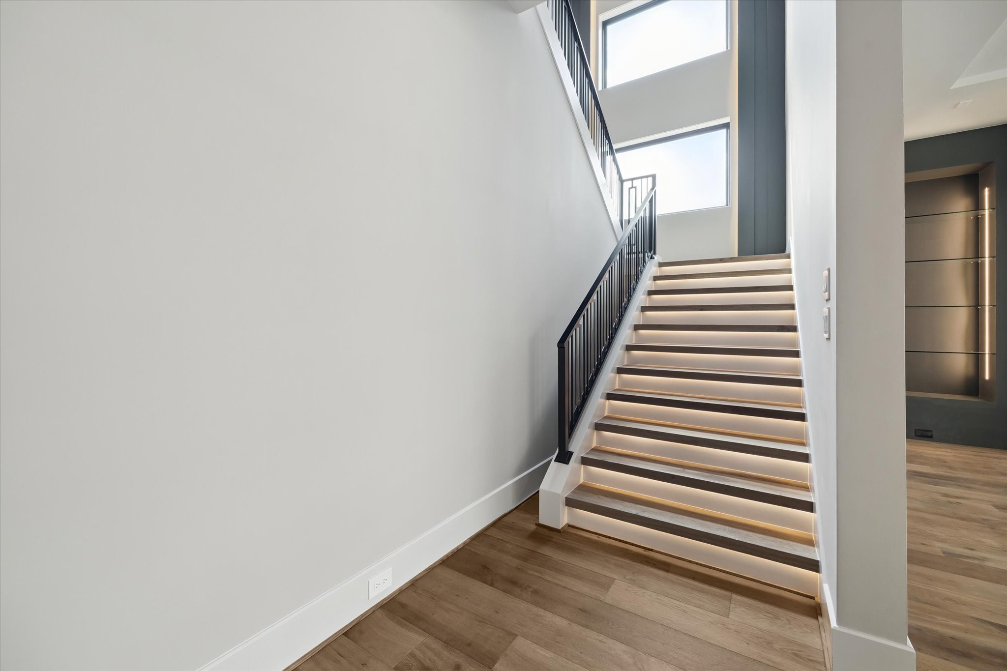 2120 Branard Street Houston, TX 77098 - Photo 14 of 33 The stairway to the second floor is a stunning architectural element, featuring lighted stair treads that add both safety and dramatic effect. A modern iron railing complements the sleek design, while large glass-pane windows with a lighted accent feature flood the space with natural light and create a striking contemporary focal point.