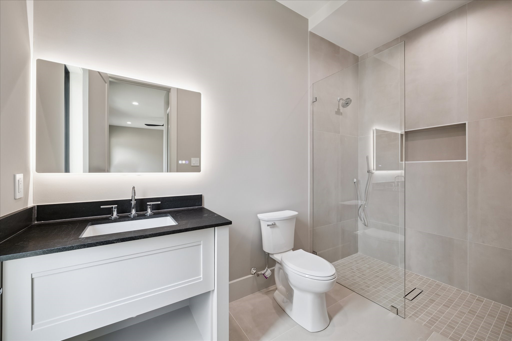 2120 Branard Street Houston, TX 77098 - Photo 23 of 33 This en-suite secondary bathroom is finished with a sleek vanity topped with a quartz counter, an undermount sink, and a modern lighted vanity mirror. A spacious walk-in shower with a built-in soap inset completes the design.