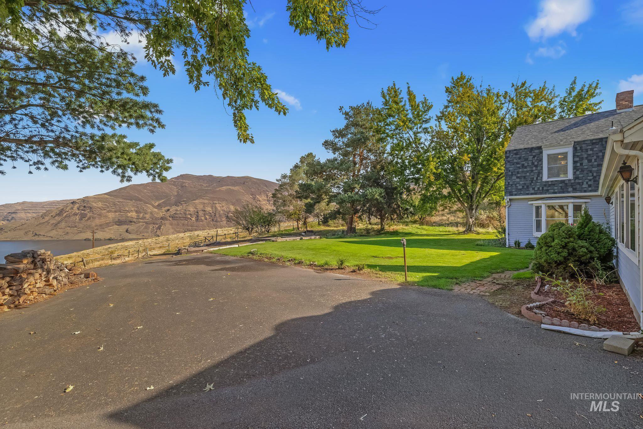 531 Silcott Road Clarkston, WA 99403 - Photo 34 of 43 Expansive paved driveway leading to a residence with light blue siding and a gambrel roof