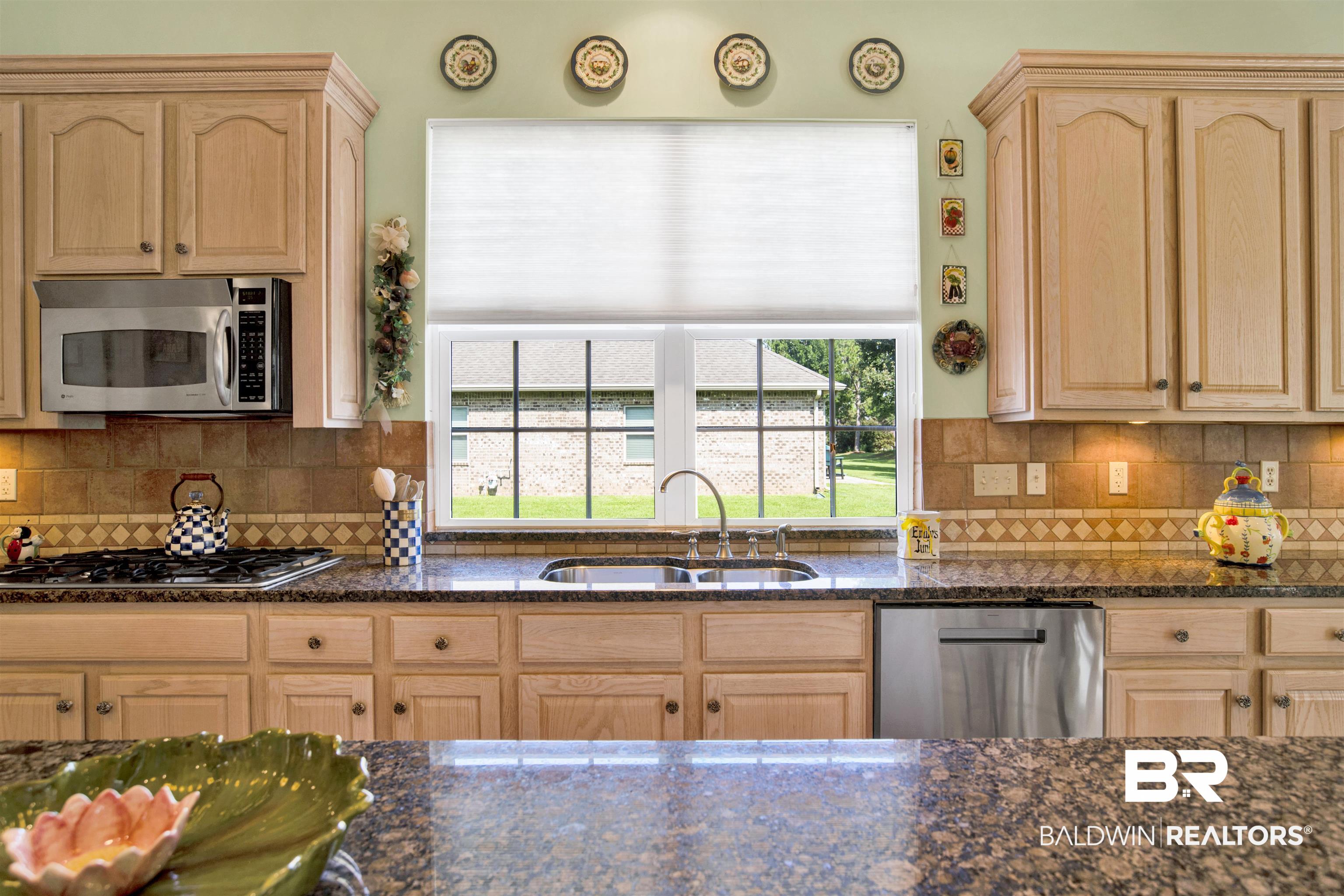 23014 Carnoustie Drive Foley, AL 36535 - Photo 33 of 49 Kitchen featuring light brown cabinetry, stainless steel appliances, decorative backsplash, and dark stone counters