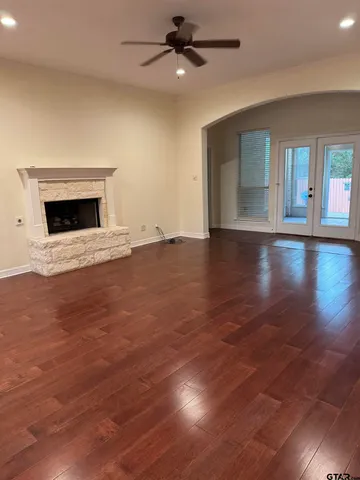an empty room with wooden floor fireplace and windows