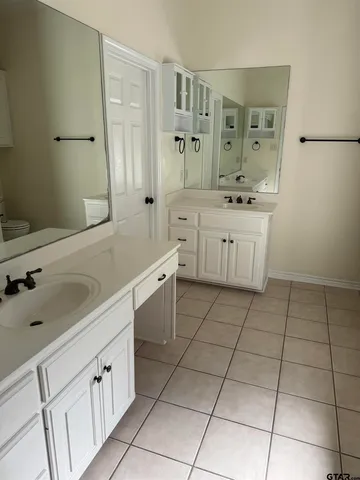 a spacious bathroom with a sink a toilet and a mirror