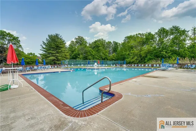 a view of a swimming pool with a bench and trees in the background