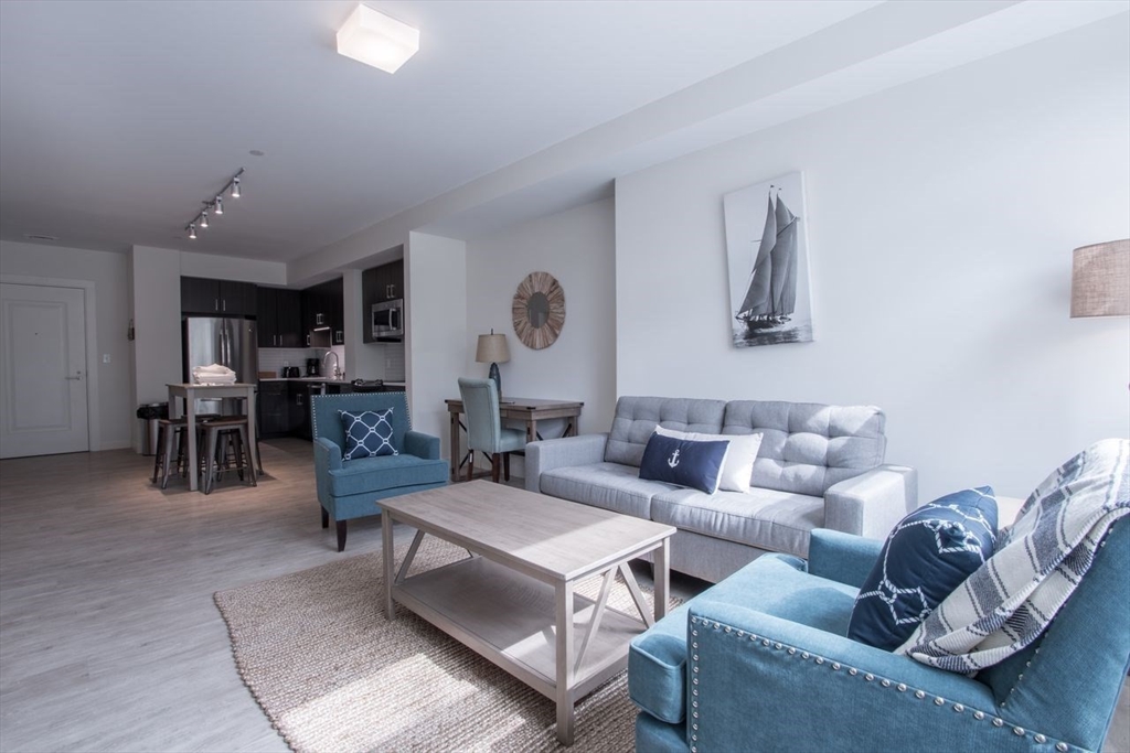 a living room with furniture kitchen view and a window