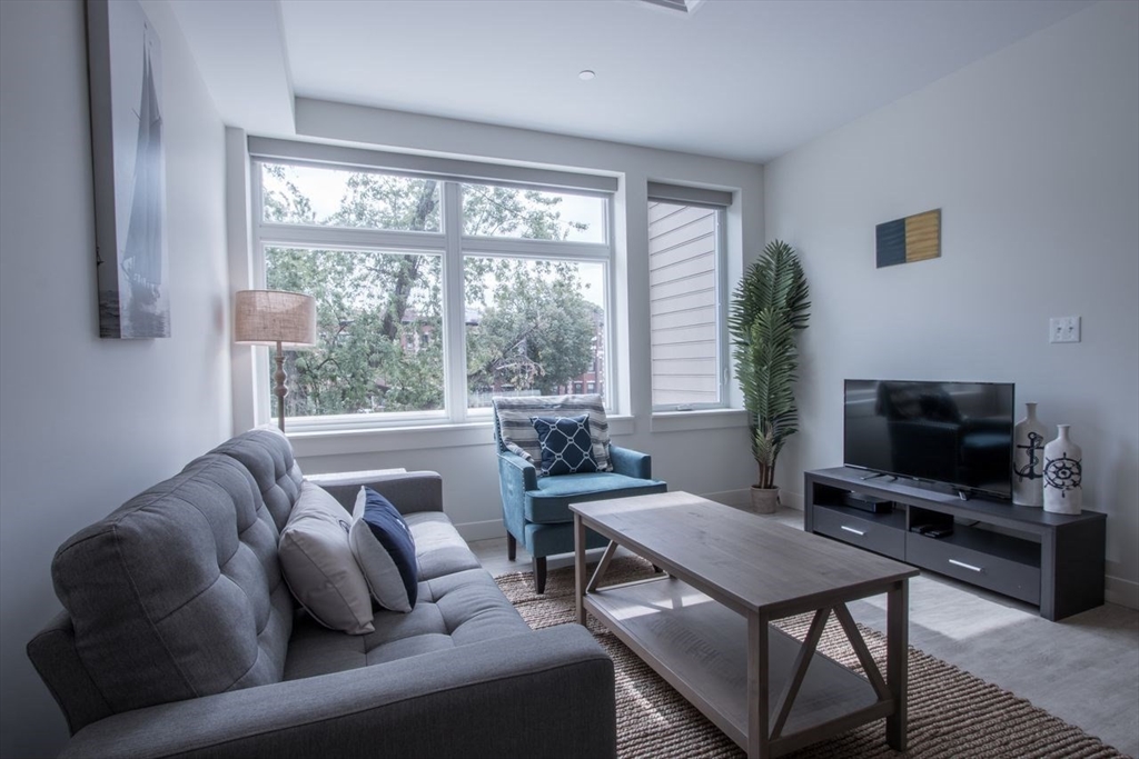 900 Beacon Street, Unit 408 Boston, MA 02215 - Photo 3 of 12 a living room with furniture a flat screen tv and a large window