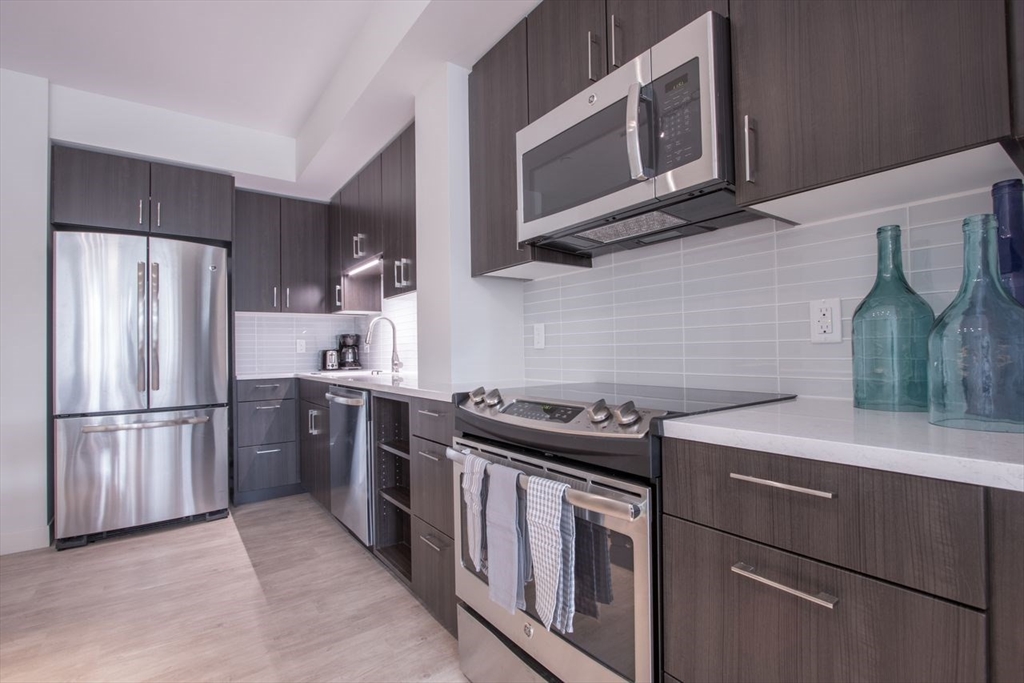 900 Beacon Street, Unit 408 Boston, MA 02215 - Photo 5 of 12 a kitchen with stainless steel appliances granite countertop a stove a refrigerator and a microwave