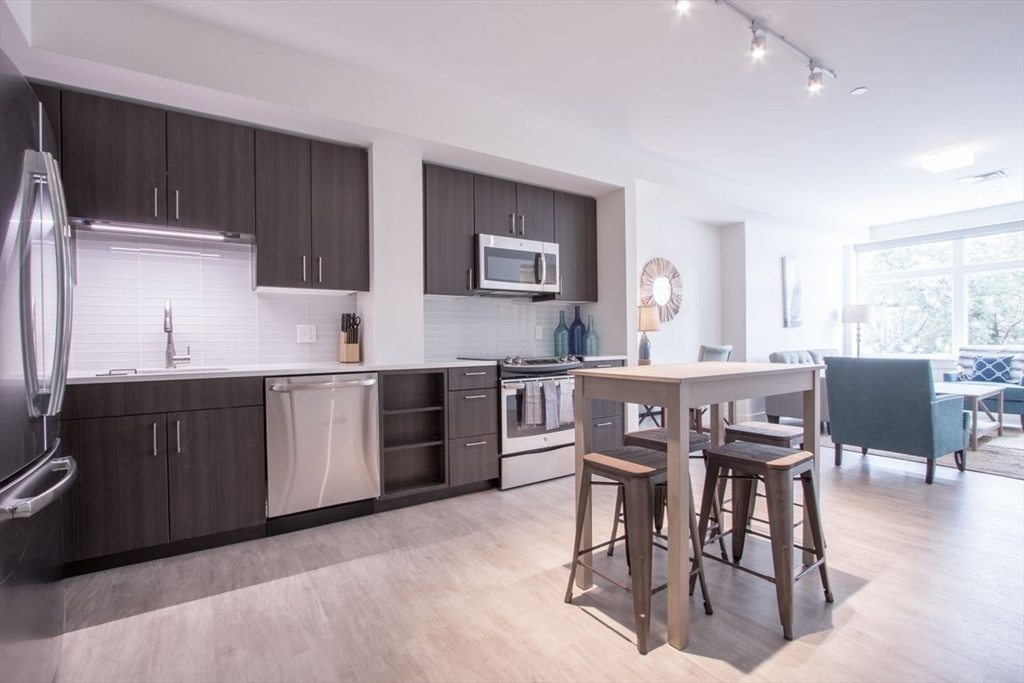 900 Beacon Street, Unit 408 Boston, MA 02215 - Photo 7 of 12 a kitchen with stainless steel appliances granite countertop a table chairs sink and cabinets