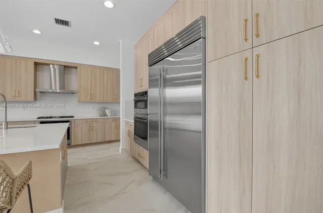 a kitchen with kitchen island a dining table chairs stainless steel appliances and cabinets