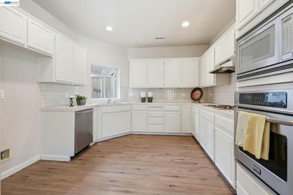 a kitchen with white cabinets stainless steel appliances and sink