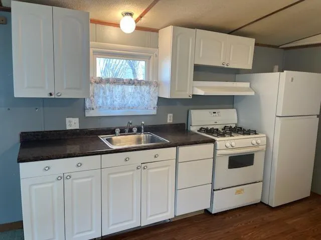 a kitchen with granite countertop white cabinets and white appliances