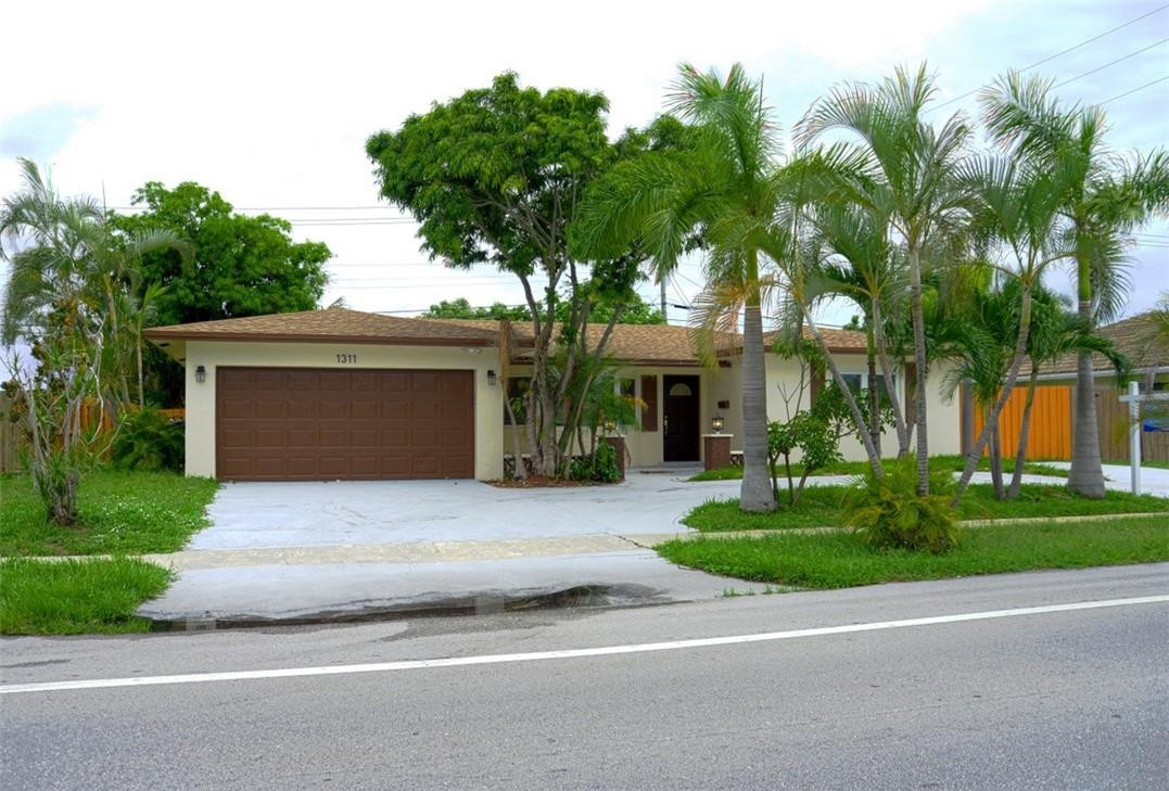 1311 Southwest 12th Avenue Boca Raton, FL 33486 - Photo 52 of 66 a front view of a house with a garden and trees