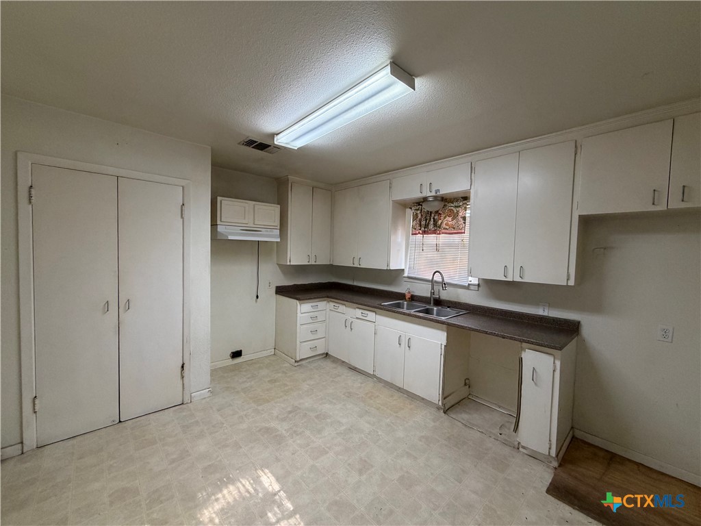 1902 Navidad Street Victoria, TX 77901 - Photo 13 of 23 a large white kitchen with granite countertop a sink and dishwasher a stove with wooden floor