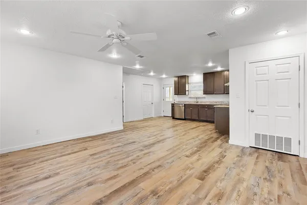 an empty room with wooden floor cabinet and windows