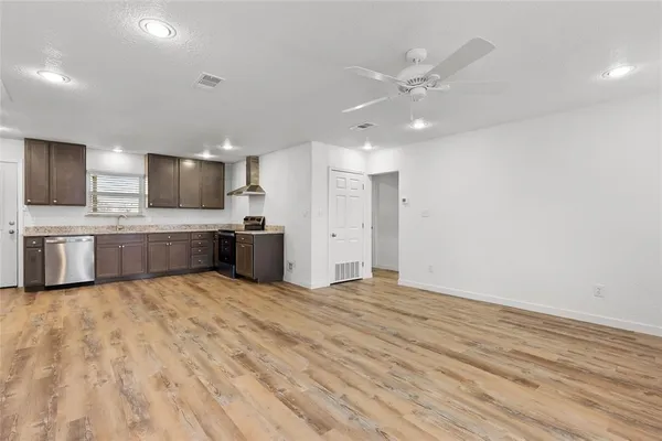 a view of kitchen with kitchen island stainless steel appliances a sink cabinets and wooden floor