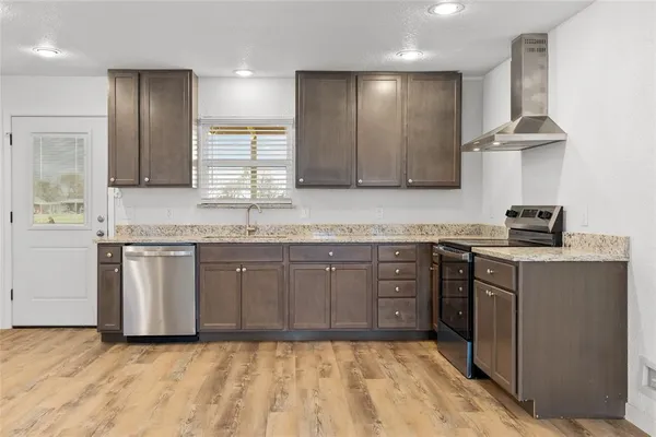 a kitchen with kitchen island granite countertop a sink cabinets and stainless steel appliances
