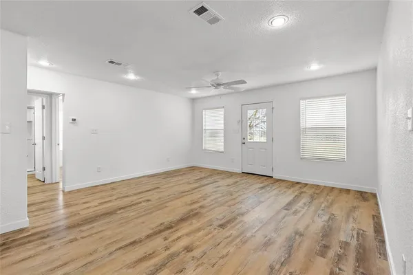an empty room with a window and a fan