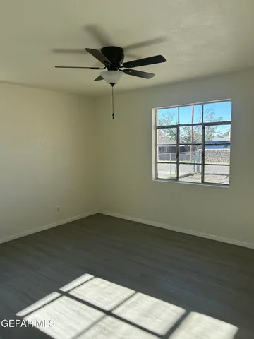 an empty room with wooden floor fan and windows