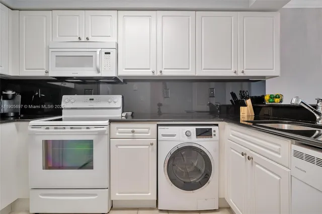 a kitchen with white cabinets and sink