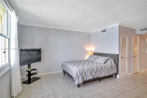a bedroom with a bed a flat screen tv and window