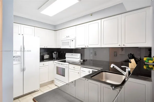 a kitchen with stainless steel appliances granite countertop a stove a sink and white cabinets
