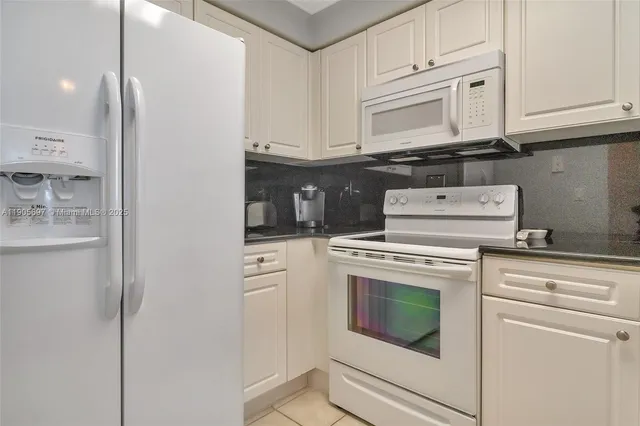 a kitchen with granite countertop white cabinets and white appliances