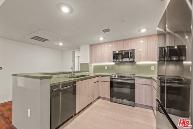 a kitchen with stainless steel appliances granite countertop a stove top oven a sink and a refrigerator