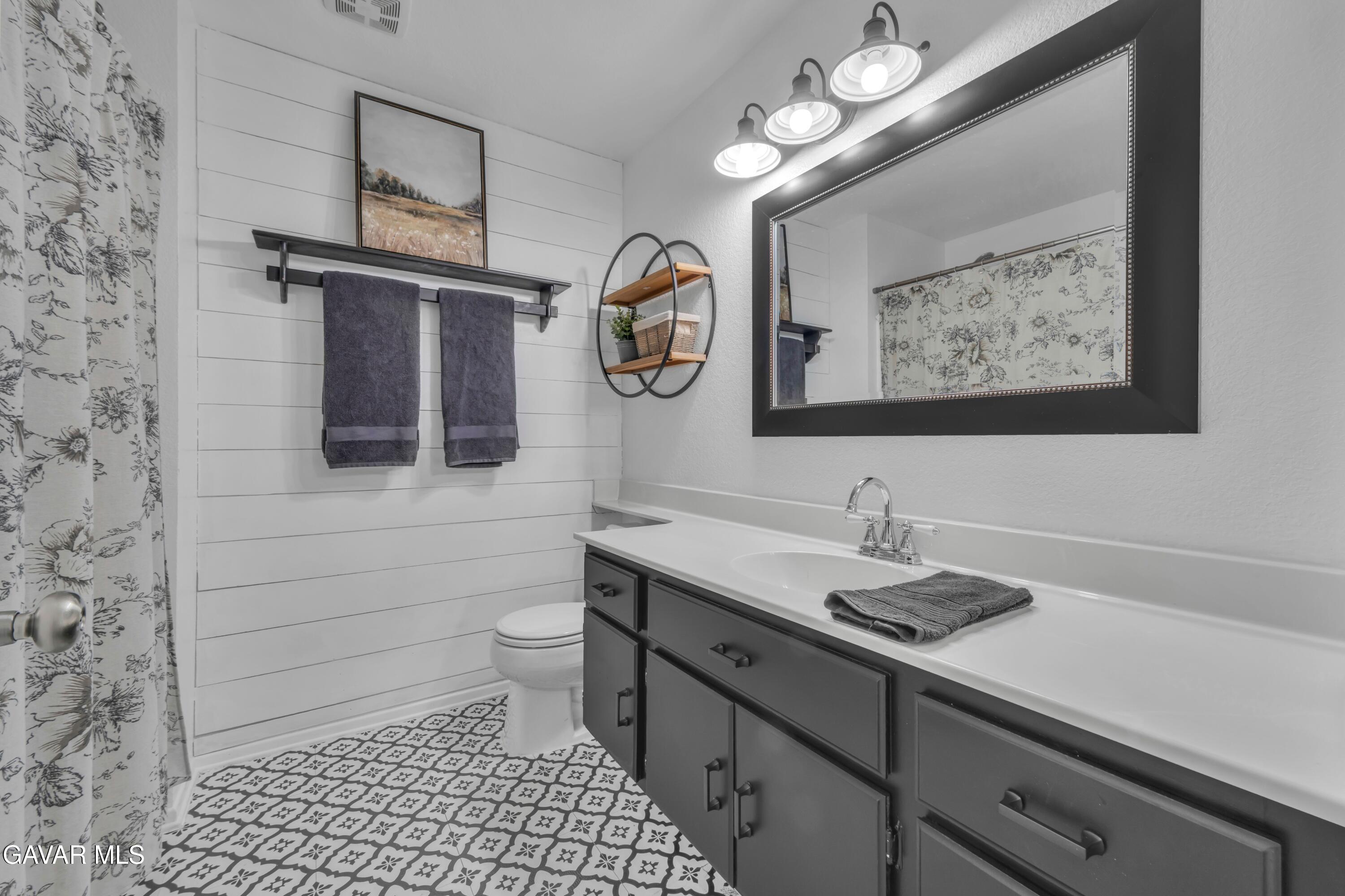 3046 Hampton Road Palmdale, CA 93551 - Photo 9 of 27 a bathroom with a sink a toilet and mirror