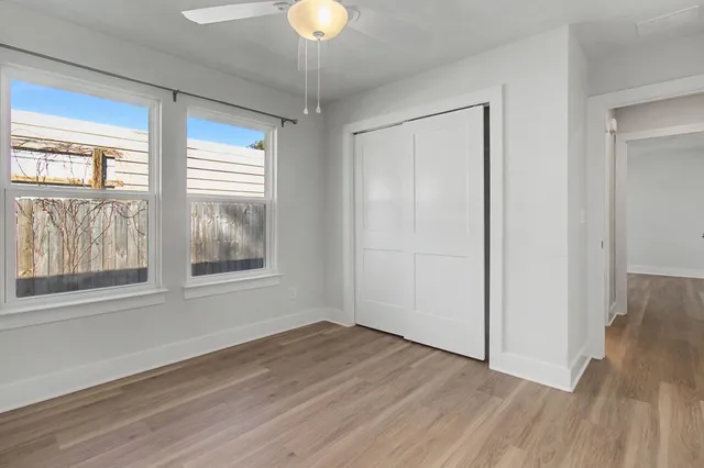 a view of an empty room with wooden floor and a window