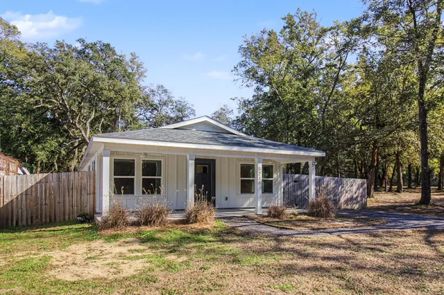 a view of a house with a small yard and wooden fence
