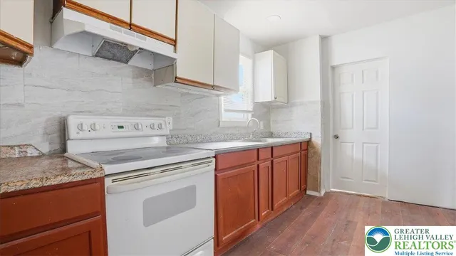 a kitchen with granite countertop a sink cabinets and wooden floor