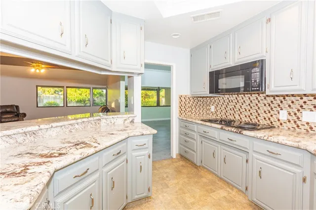 a kitchen with granite countertop white cabinets and white appliances