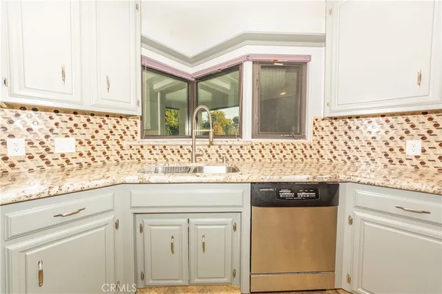 a kitchen with granite countertop white cabinets and sink