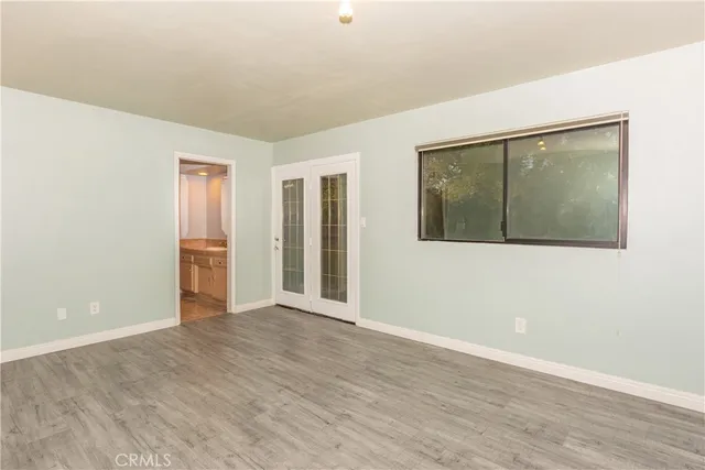 a view of an empty room with wooden floor and closet