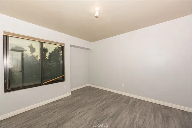 a view of an empty room with wooden floor and windows