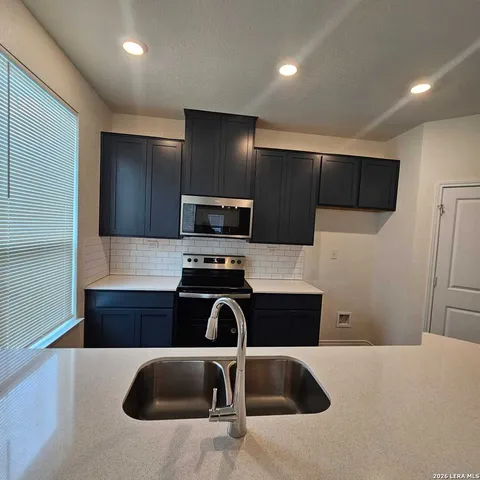 a kitchen with a sink a microwave a refrigerator and cabinets