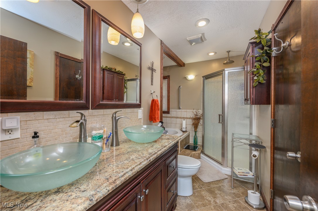 2667 Deibel Road Clinton, OH 44216 - Photo 13 of 23 Bathroom featuring a shower with door, a textured ceiling, toilet, tile patterned floors, and decorative backsplash