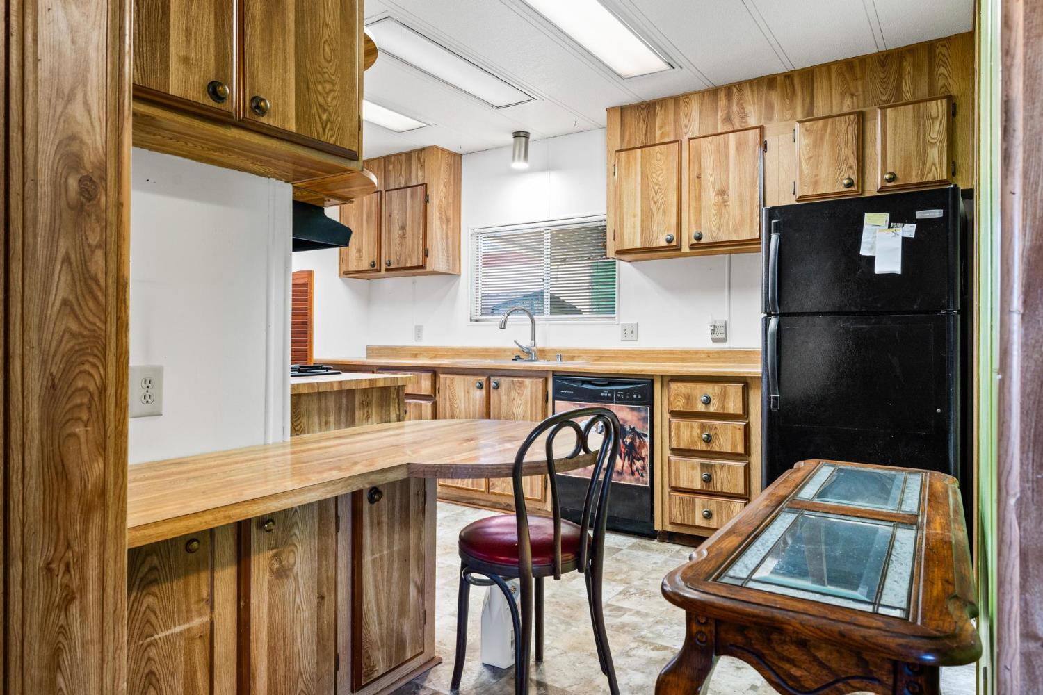 1200 South Carpenter Road, Unit 4 Modesto, CA 95351 - Photo 13 of 31 Kitchen featuring extensive wood-finish cabinetry, wood-finish countertops, black dishwasher, and a stainless steel sink. Refrigerator not available