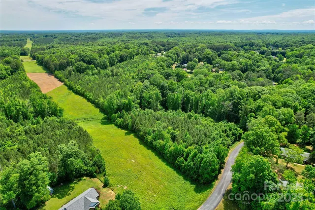 an aerial view of residential houses with outdoor space and trees all around